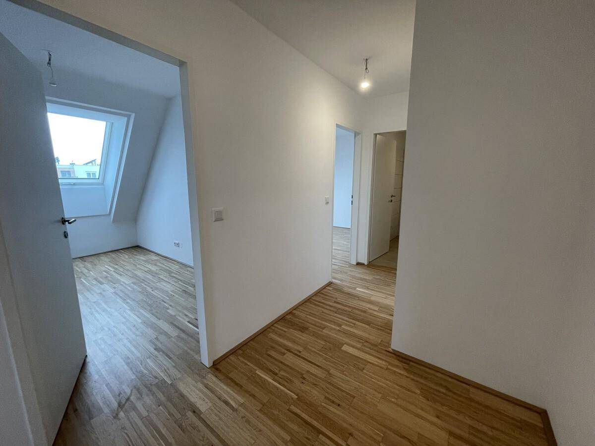 Heller Flur mit Parkettboden, der zu verschiedenen Räumen der Wohnung führt.