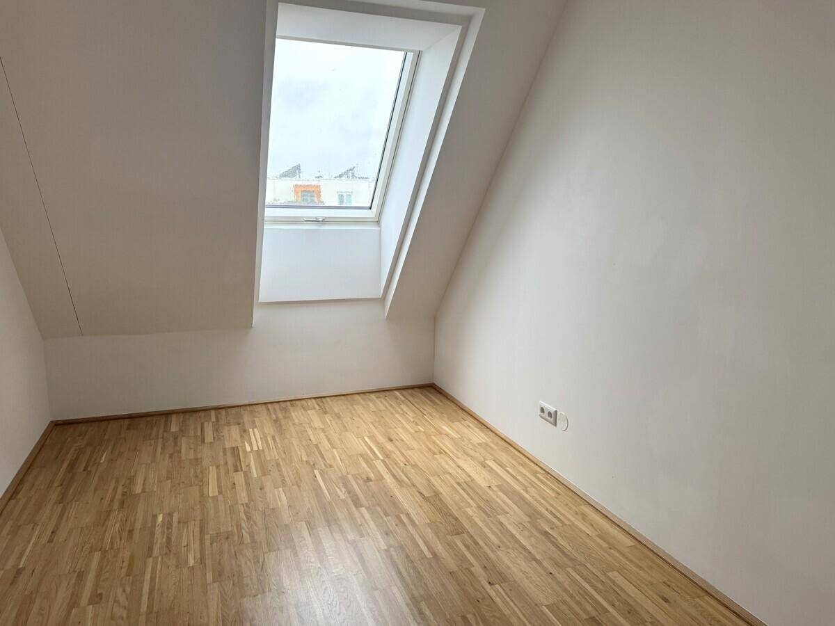 Gemütlicher Raum im Dachgeschoss mit Parkettboden und einem Dachfenster für natürliches Licht.
