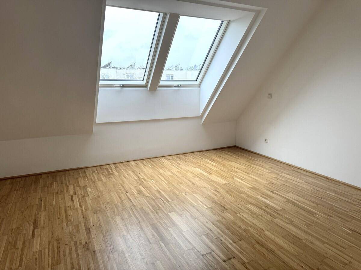 Heller Dachgeschossraum mit Parkettboden und zwei Dachfenstern, ideal als Schlafzimmer.
