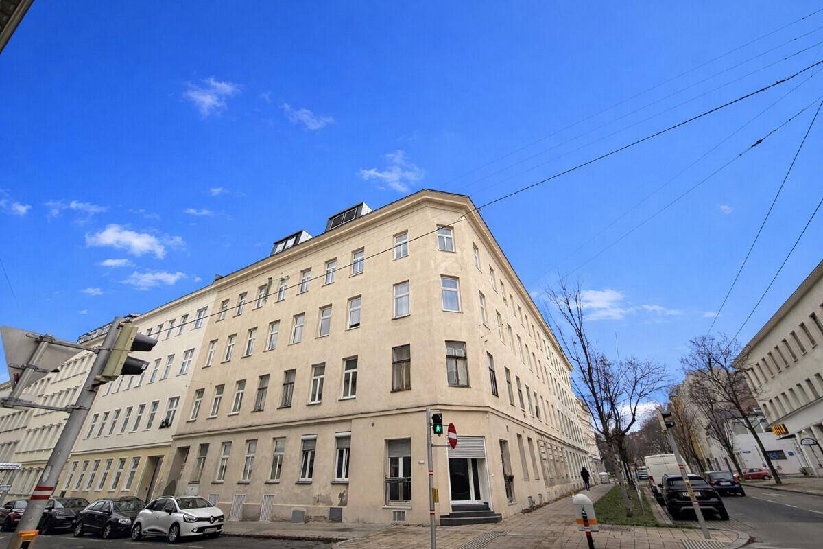 Eckgebäude mit klassischer Fassade und vielen Fenstern an einem sonnigen Tag.