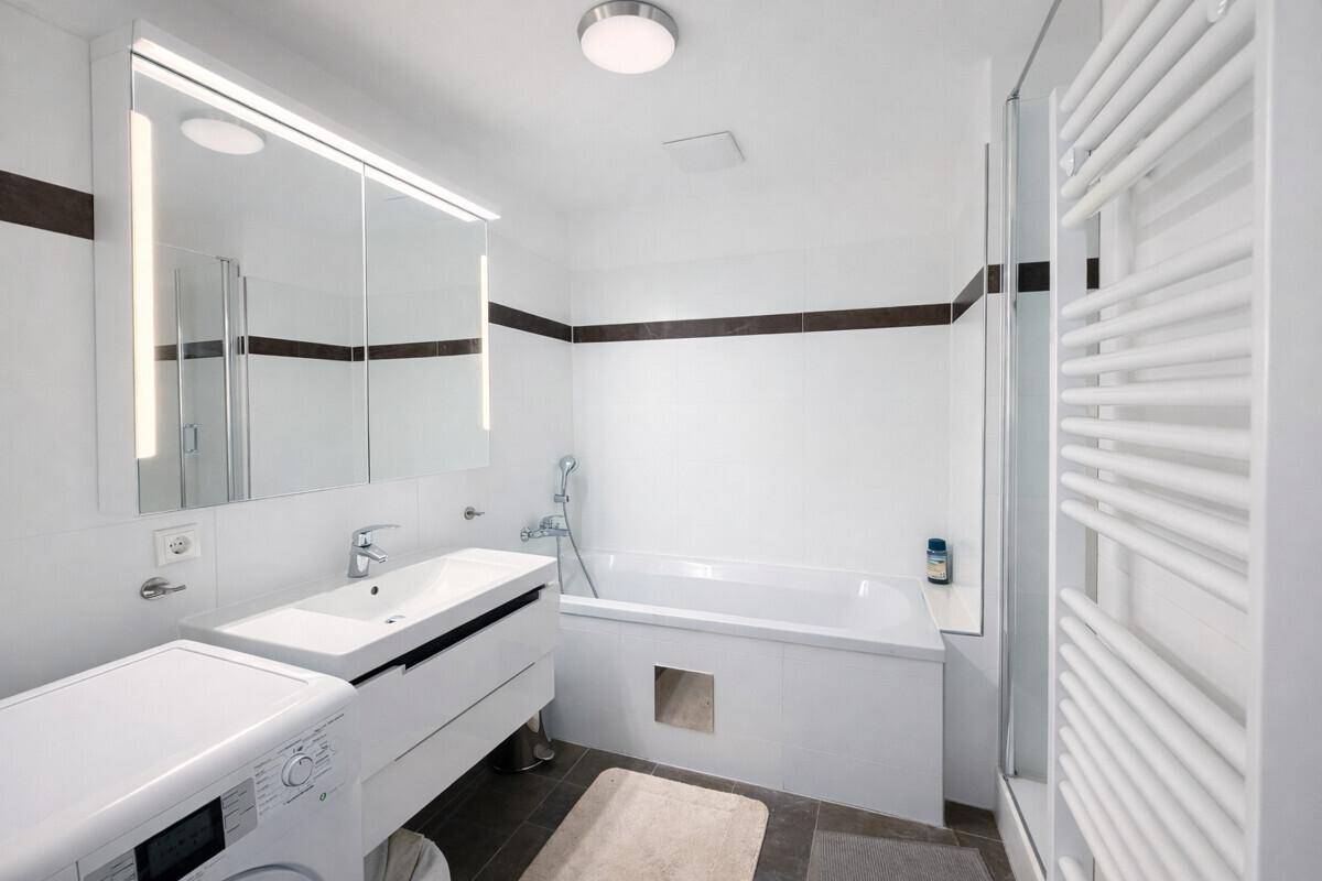 Modernes Badezimmer mit Badewanne, Dusche, Waschbecken und beheiztem Handtuchhalter.