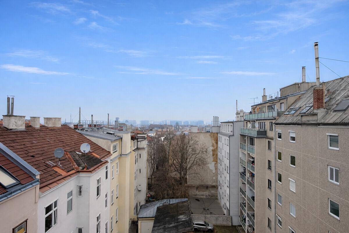 Weitläufiger Blick über die Dächer der Stadt unter blauem Himmel.