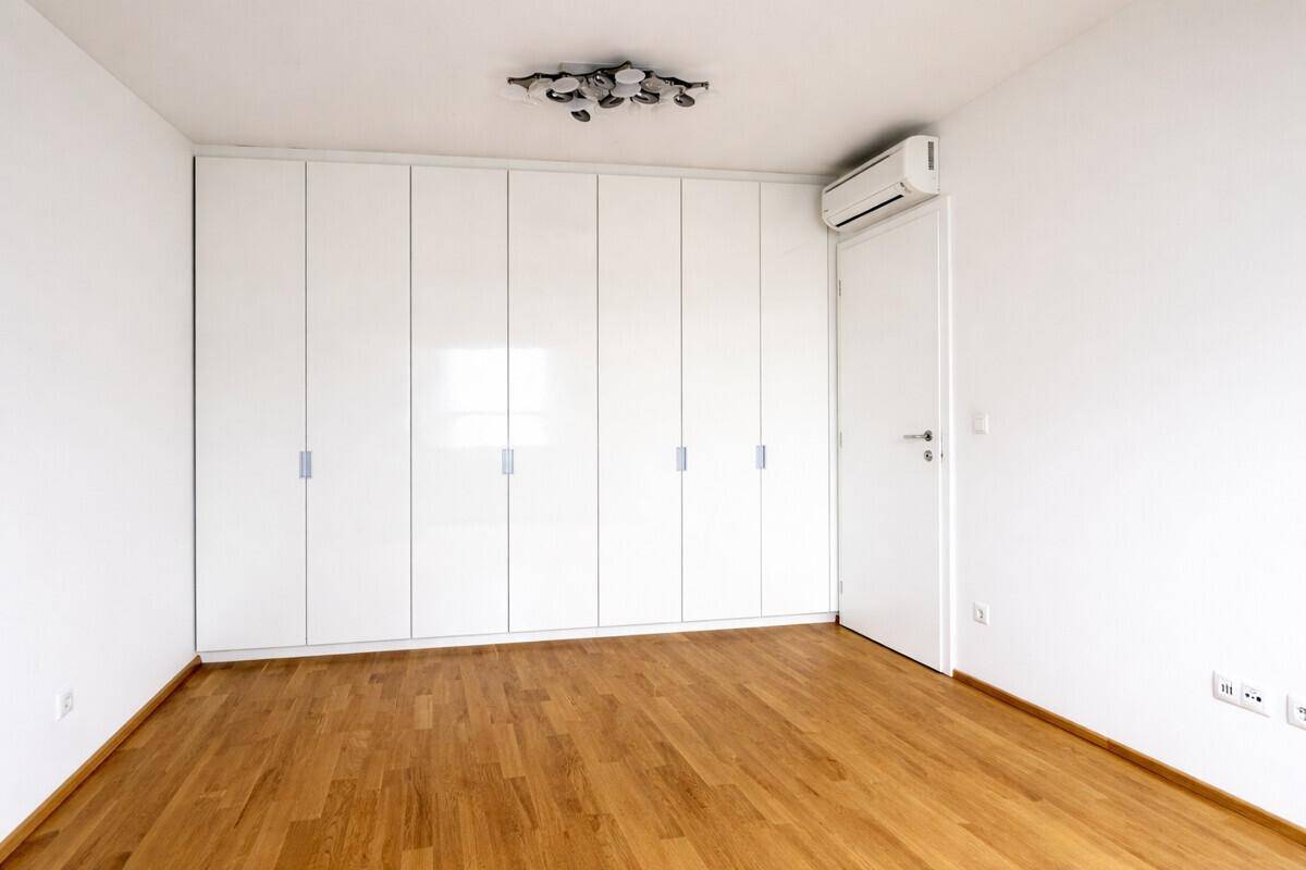 Schlafzimmer mit großem Einbauschrank, Holzboden und Klimaanlage.