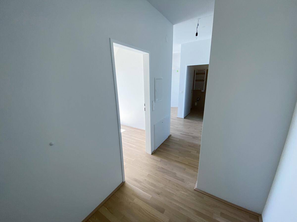 Heller Flur mit Holzboden, der zu verschiedenen Zimmern der Wohnung führt.