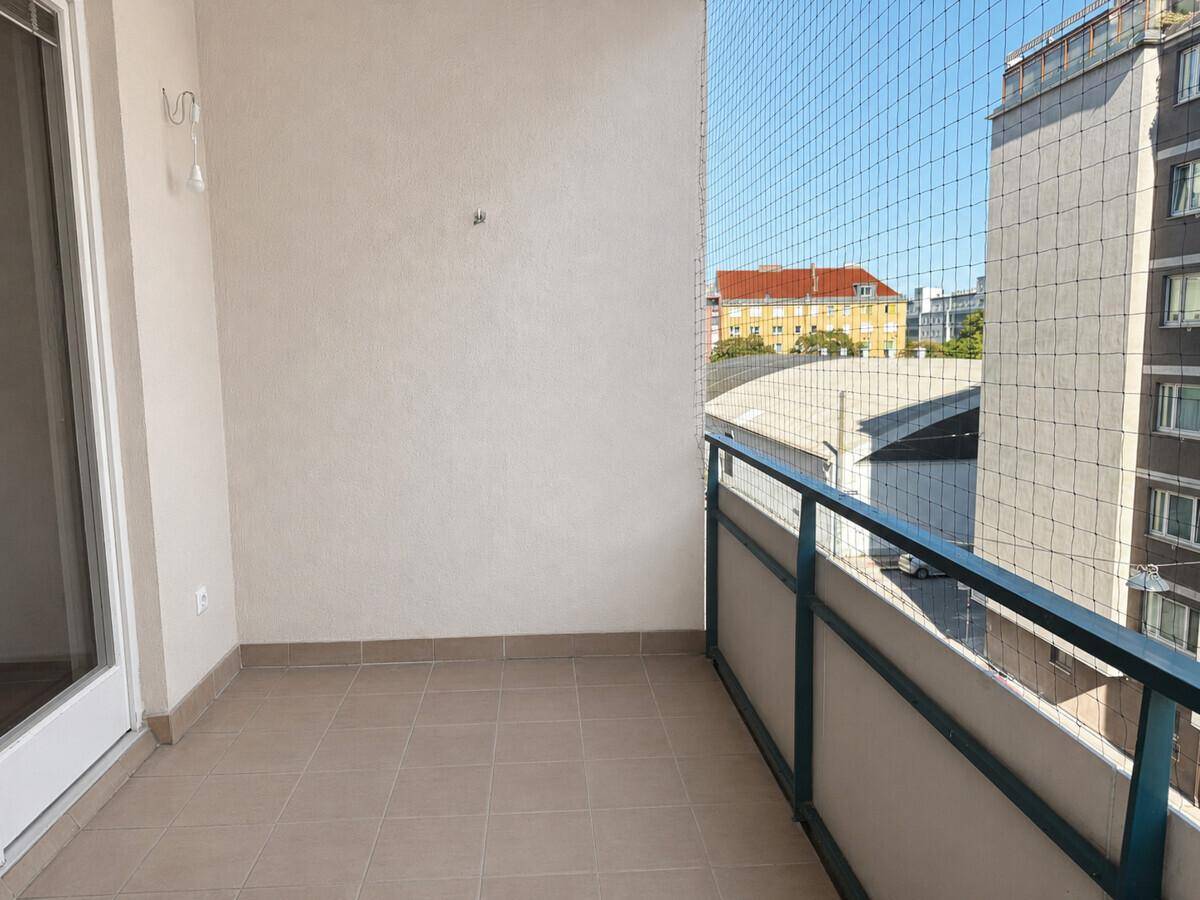 Geräumiger Balkon mit Fliesenboden, Metallgeländer und Stadtblick, gesichert mit einem Netz.