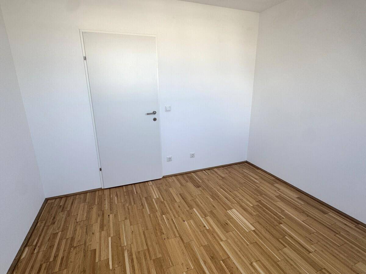 Kleineres, helles Zimmer mit Parkettboden und weiß gestrichenen Wänden, ideal als Kinderzimmer.