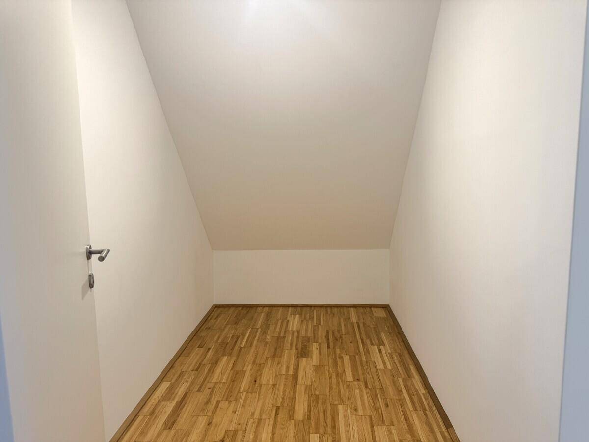 Praktischer Abstellraum mit Parkettboden und schräger Decke, ideal für zusätzlichen Stauraum.