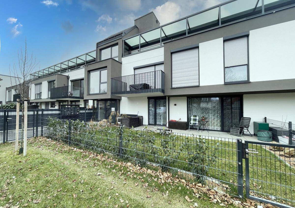 Reihen moderner Gebäude mit Terrassen und kleinen Vorgärten in einer Wohnsiedlung.