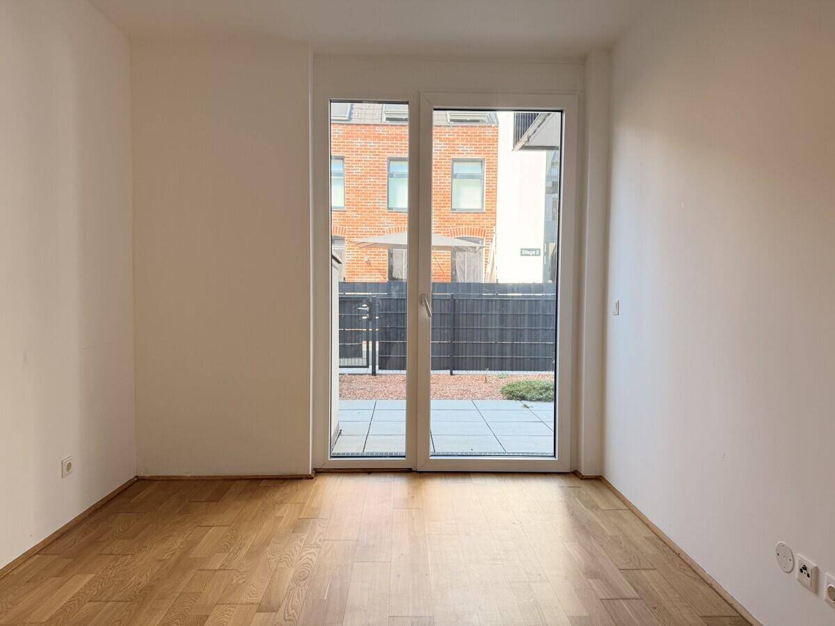 Helles Zimmer mit Holzboden und Zugang zu einem privaten Außenbereich.