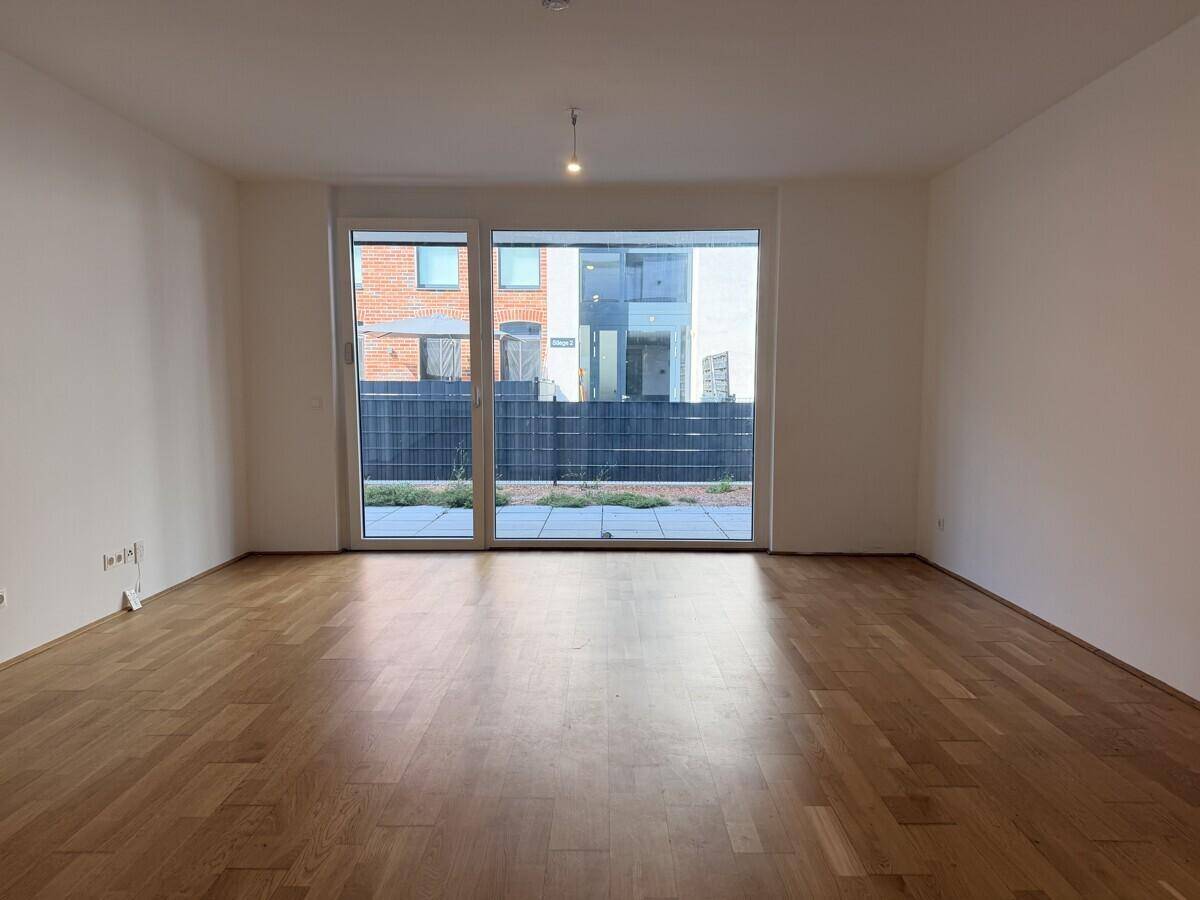 Geräumiges Wohnzimmer mit großen Fenstern und direktem Zugang zu einer Terrasse.