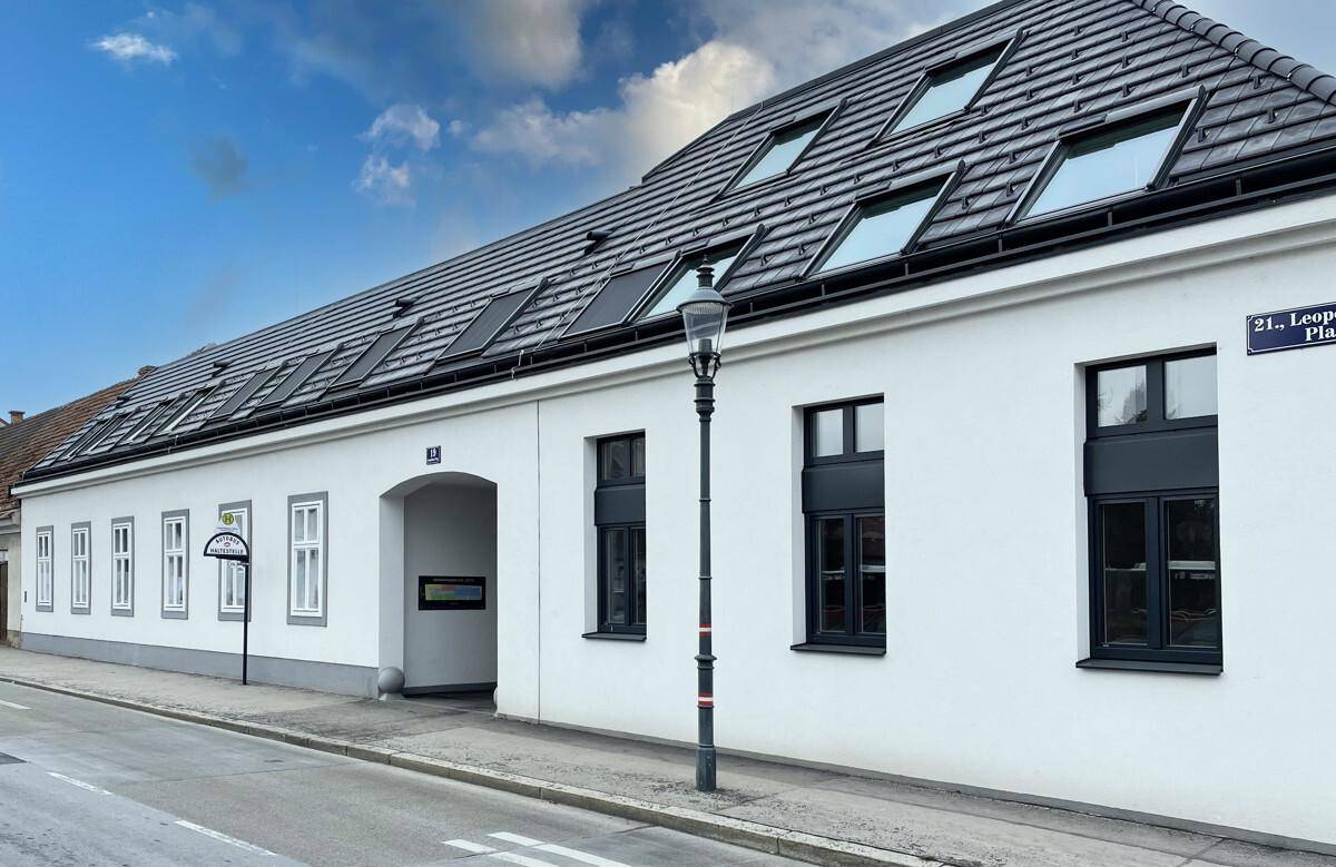 Renoviertes Gebäude mit moderner Dachkonstruktion und Gaubenfenstern an einer Straße.