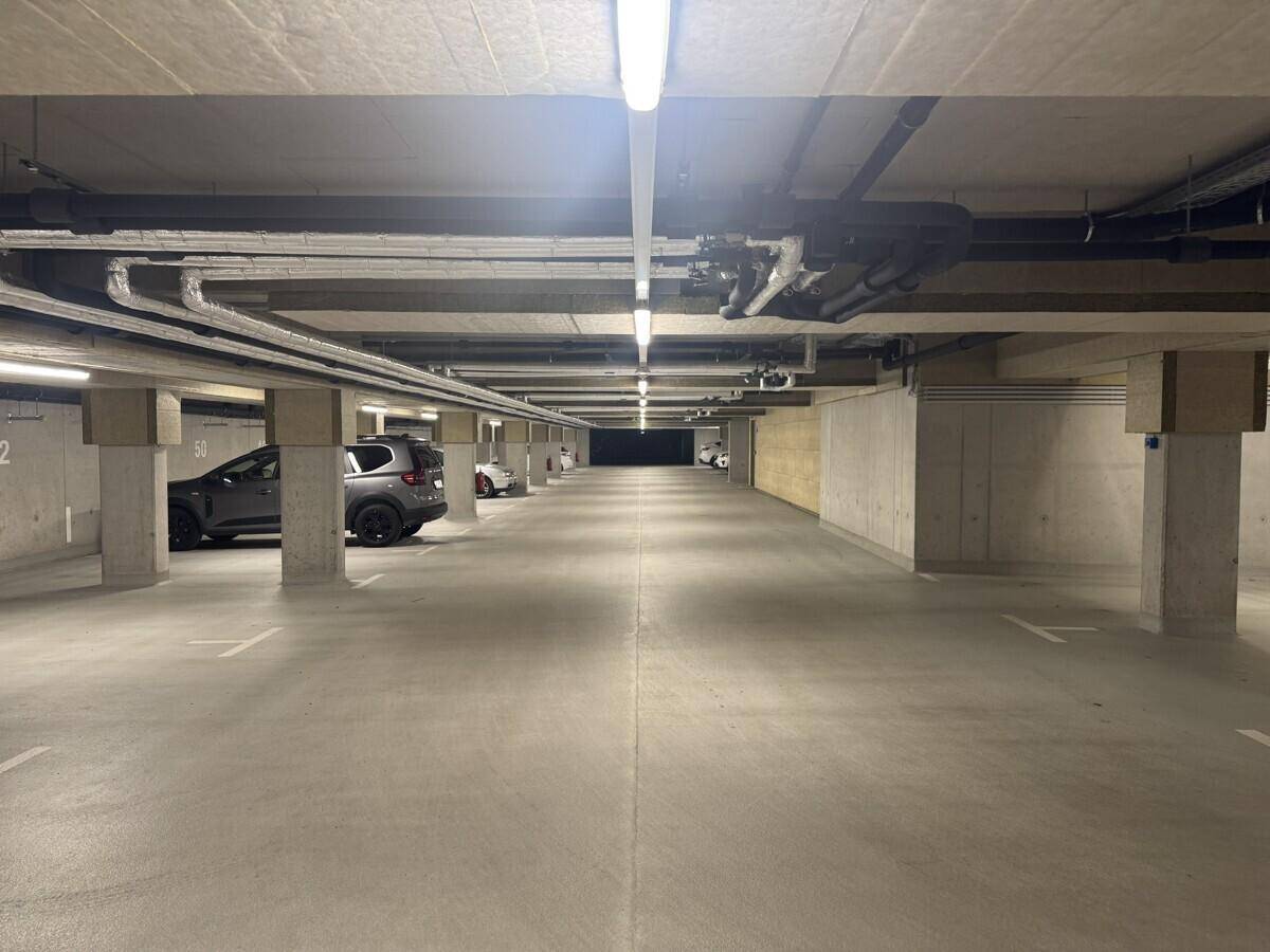 Weitläufige Tiefgarage mit zahlreichen leeren Stellplätzen und sichtbaren Deckeninstallationen.
