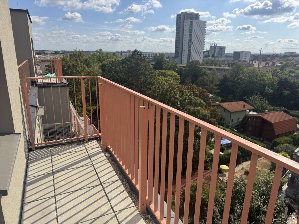 Sonniger Balkon mit Fliesenboden und Panoramablick auf die Stadt und viel Grün.