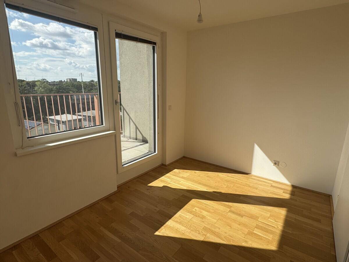 Helles Zimmer mit Holzboden und direktem Zugang zu einem Balkon.