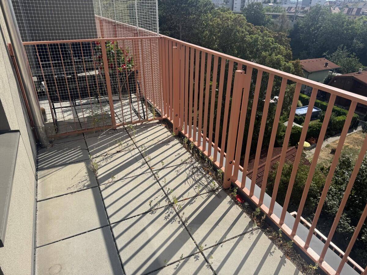 Terrasse mit Fliesenboden und Metallgeländer, umgeben von Bäumen und Natur.