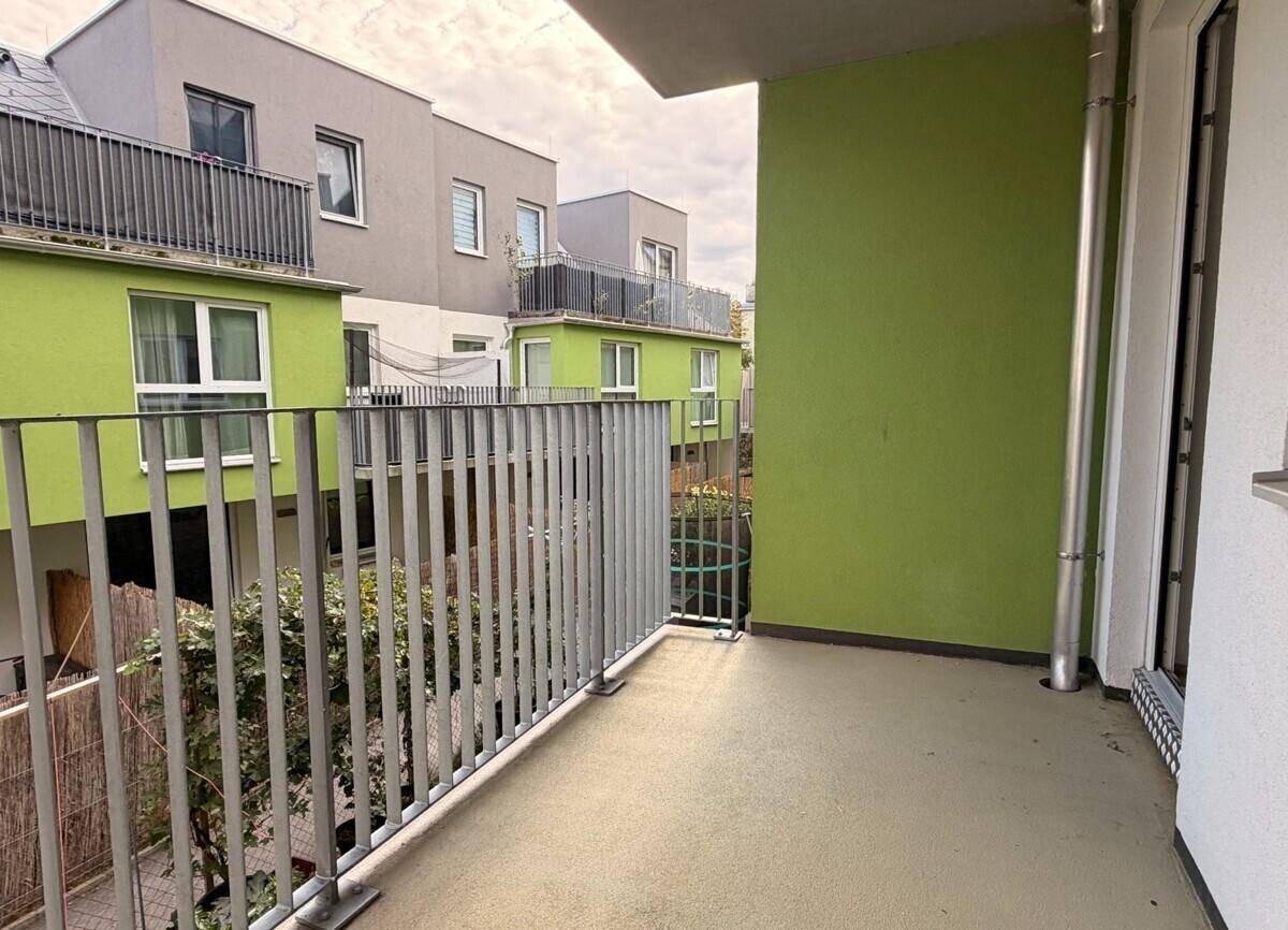 Geräumiger Balkon mit Blick auf die moderne Wohnanlage und den begrünten Innenhof.
