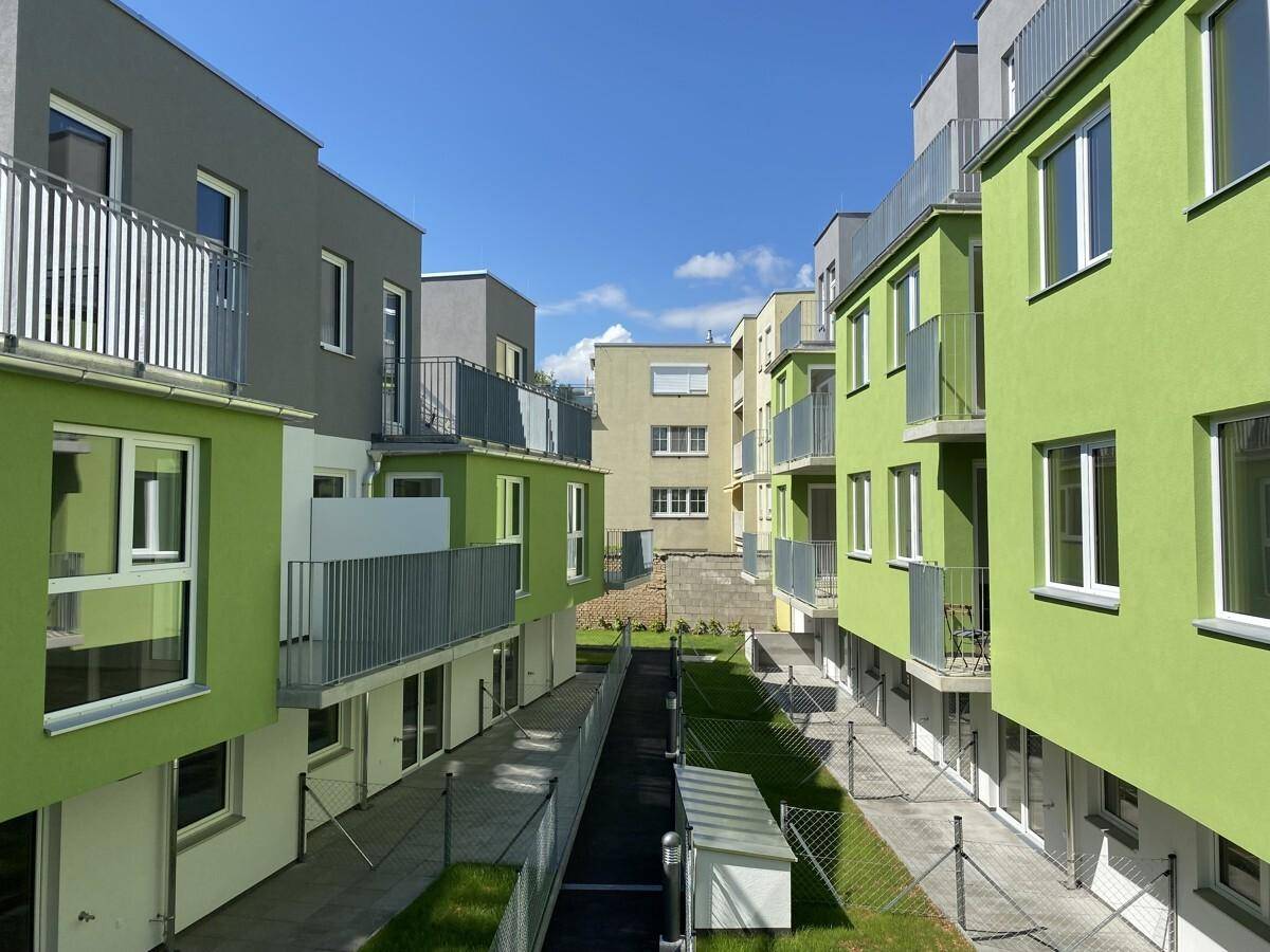 Moderne Wohnanlage mit farbigen Fassaden und Balkonen unter blauem Himmel.