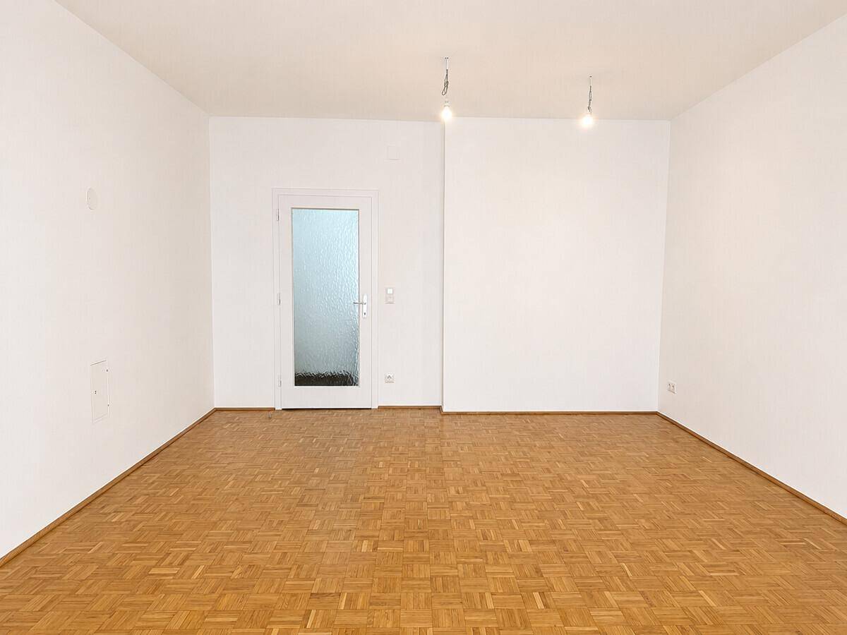 Geräumiges Zimmer mit klassischem Parkettboden und einer Tür mit Milchglas, bereit zur individuellen Gestaltung.