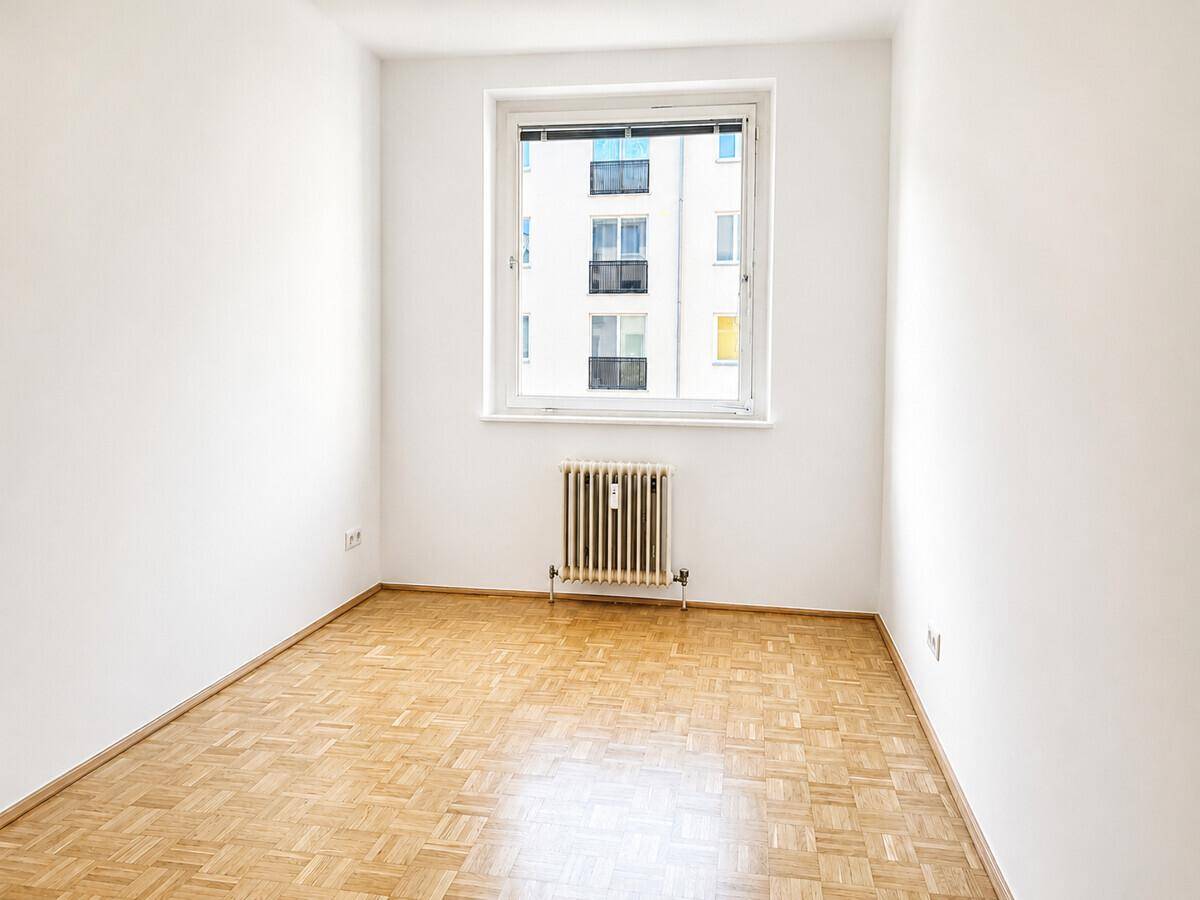 Kleineres Zimmer mit Parkettboden, Fenster und Heizkörper, ideal als Schlaf- oder Arbeitszimmer.