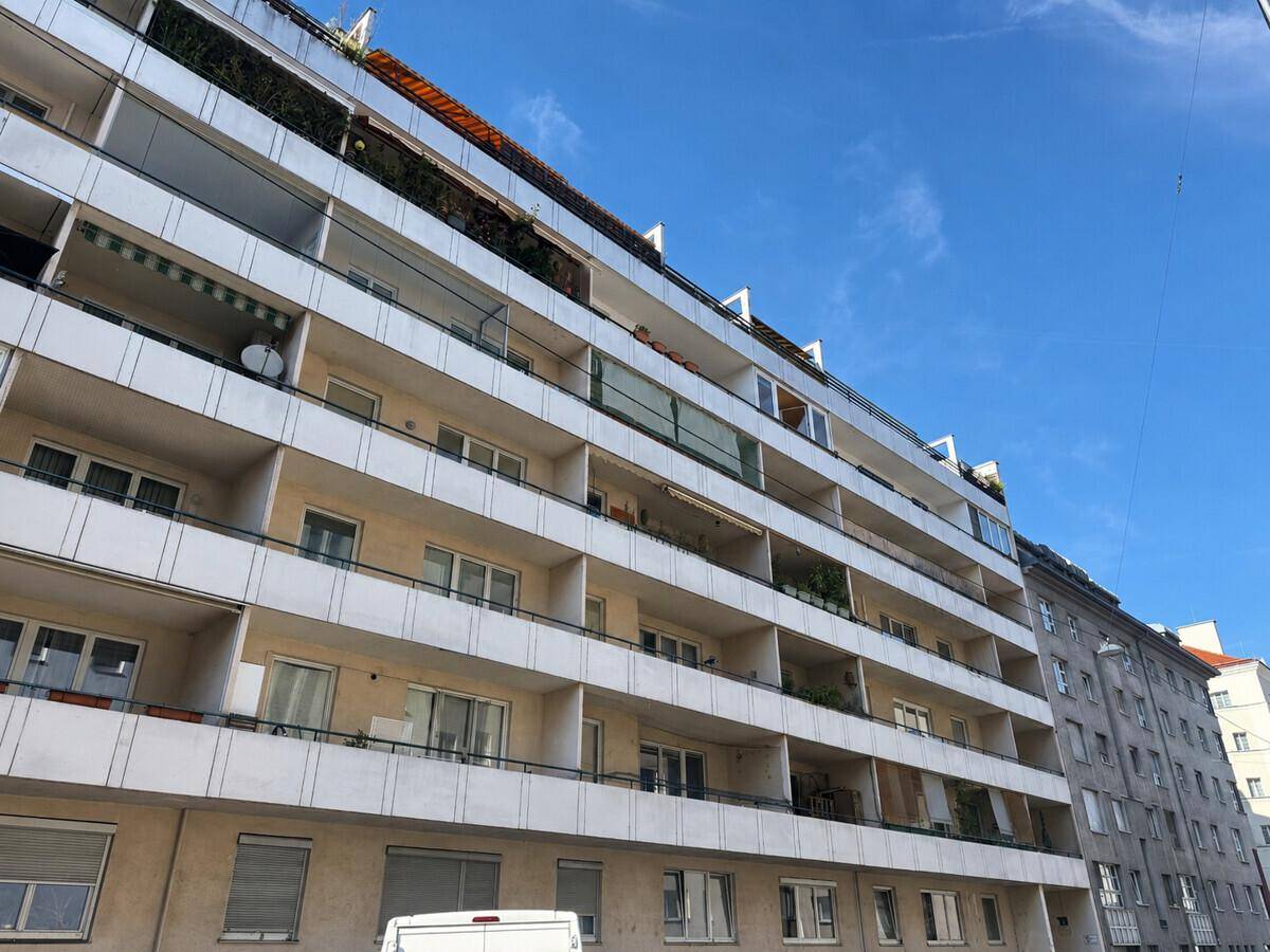 Mehrstöckiges Wohngebäude mit zahlreichen Balkonen unter blauem Himmel, typisch für städtische Architektur.
