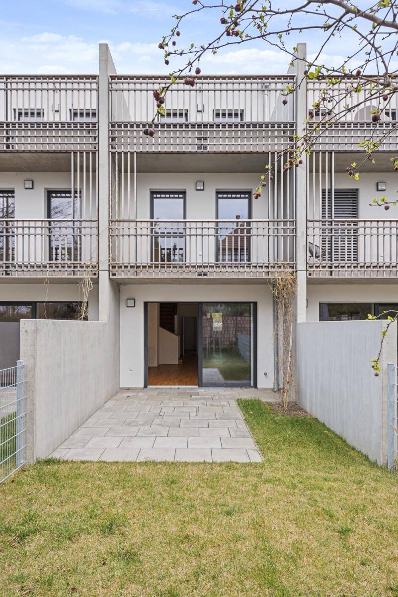 Rückseite des modernen Reihenhauses mit kleiner Terrasse und privatem Gartenbereich.