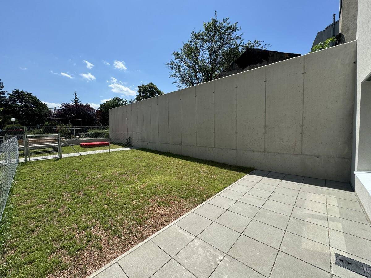 Kleiner privater Gartenbereich mit Rasenfläche und gepflasterter Terrasse neben dem Gebäude.