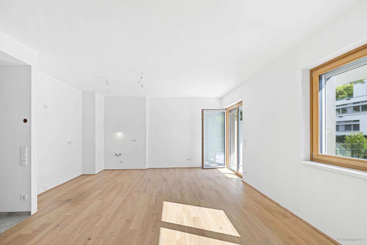 Lichtdurchfluteter Raum mit Holzboden und direktem Zugang zu einem Außenbereich.