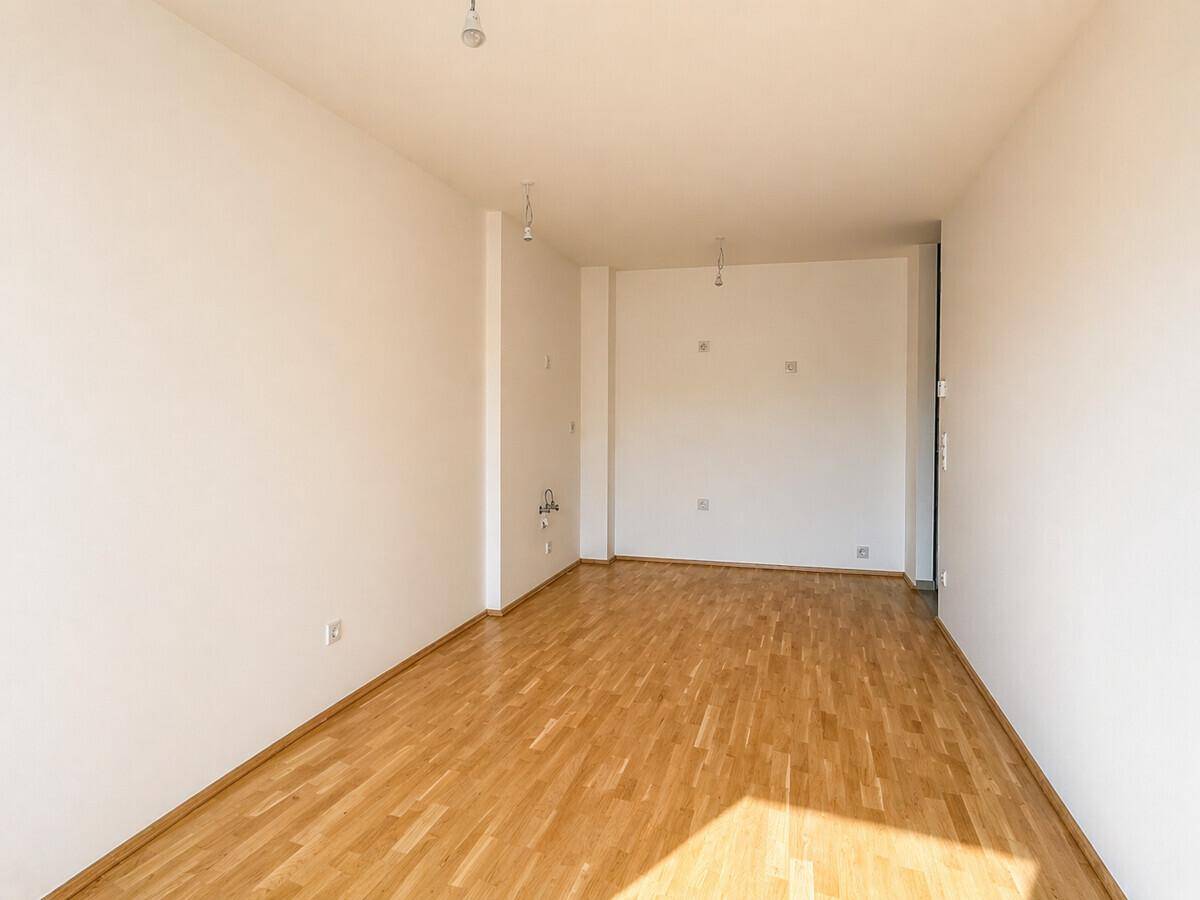 Geräumiges, unmöbliertes Zimmer mit hellem Holzfußboden, bereit für individuelle Gestaltung.
