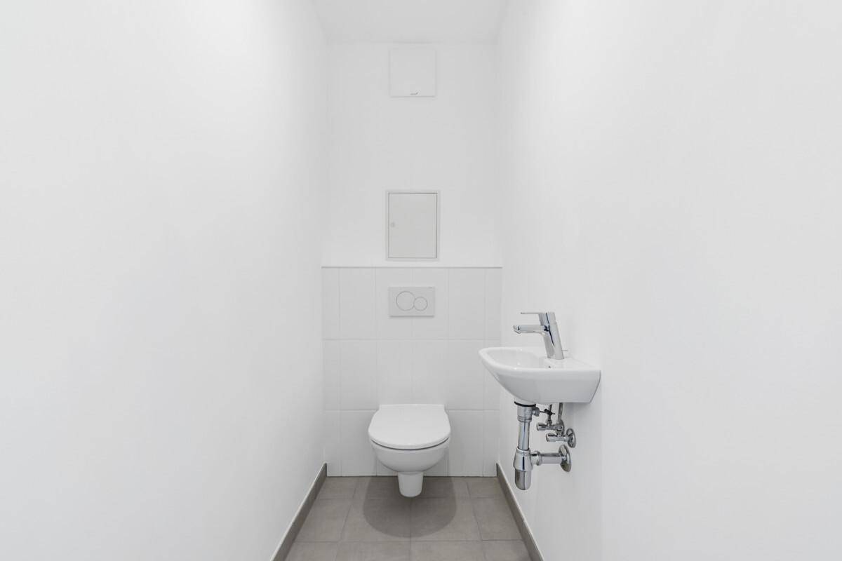 Modernes Gäste-WC mit wandhängender Toilette und kleinem Waschbecken in minimalistischem Design.