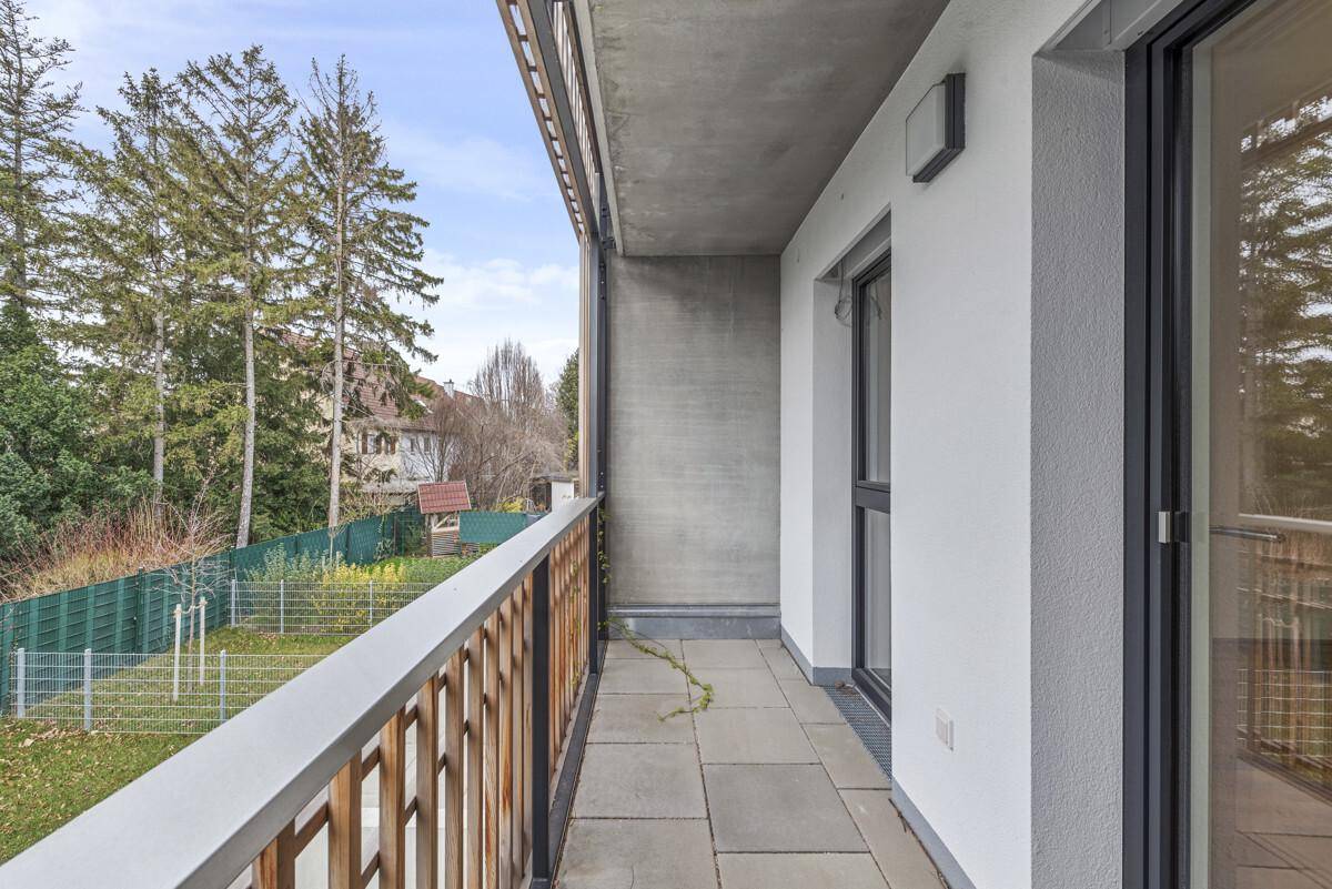 Langer Balkon mit Fliesenboden und Blick ins Grüne.