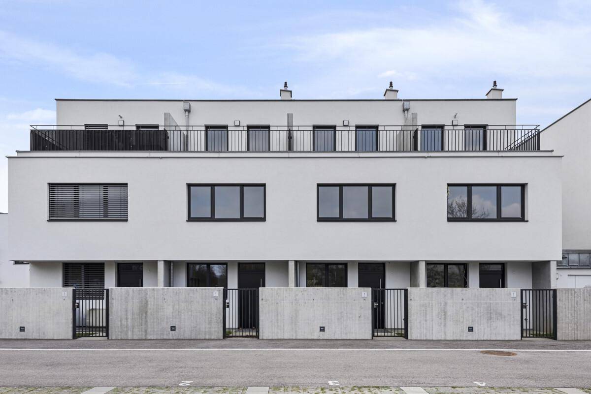 Moderne Reihenhäuser mit weißer Fassade und flachen Dächern.