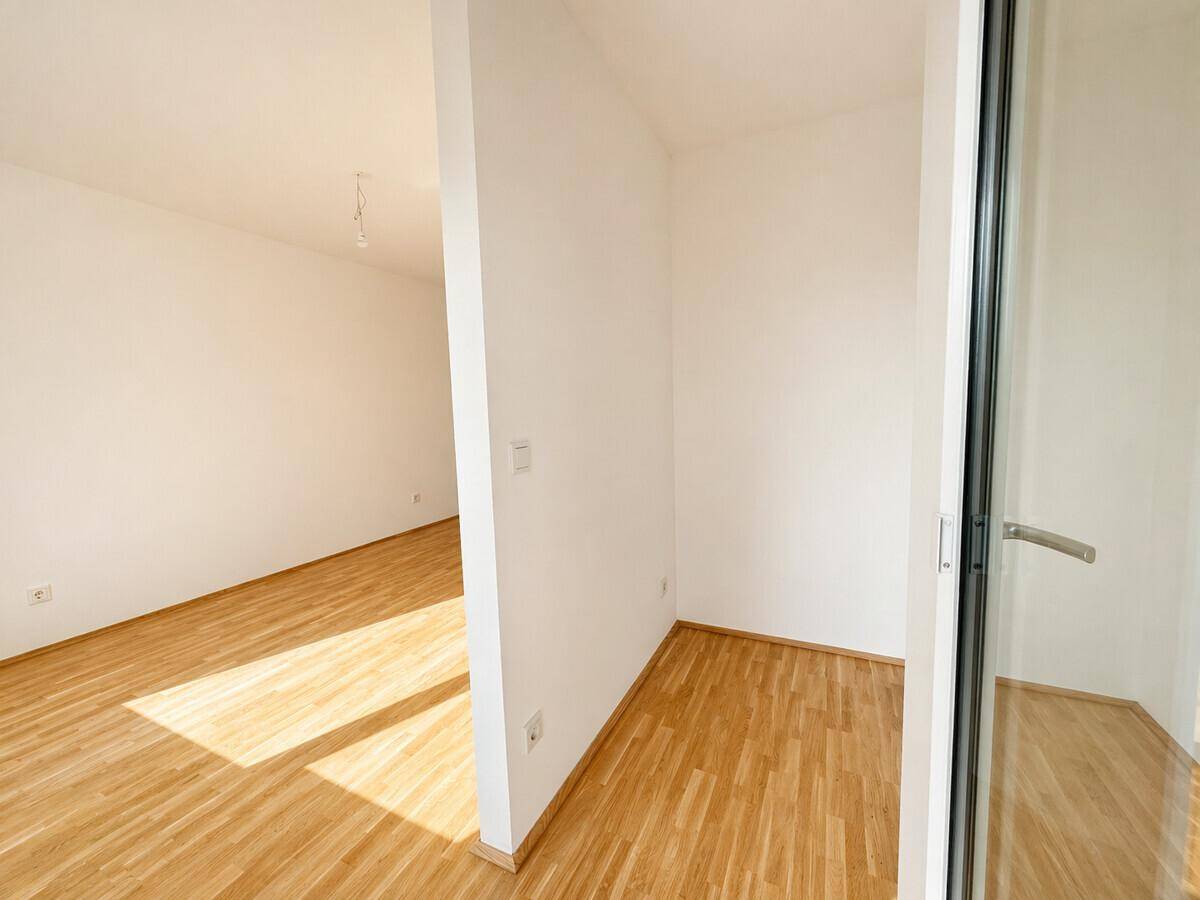 Heller Innenraum mit Parkettboden und weißen Wänden, der vielseitig genutzt werden kann.