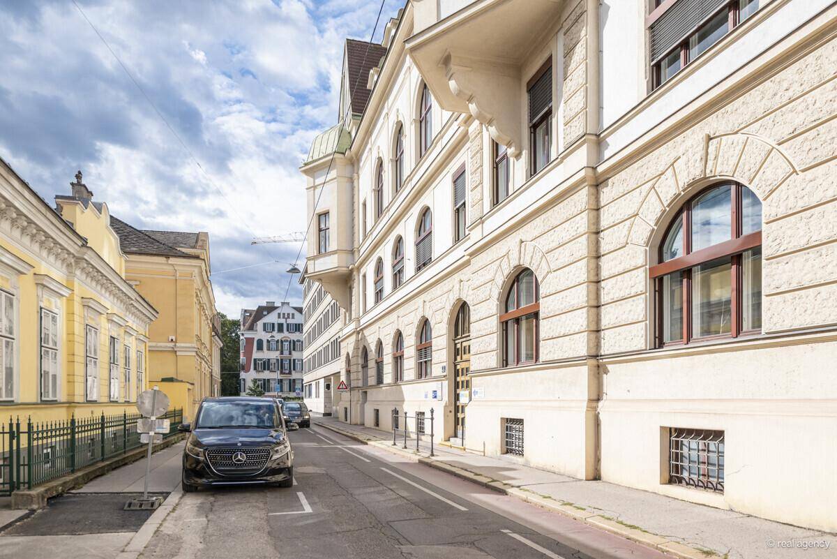Historische Straßenansicht mit einem eleganten Gebäude und geparktem Auto.
