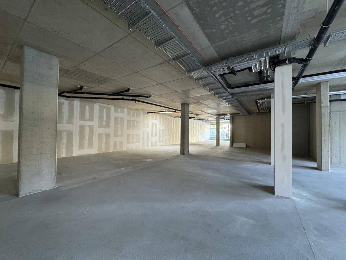 Großer, unfertiger Gewerberaum mit Betonboden, sichtbaren Leitungen und vorbereiteten Trockenbauwänden.