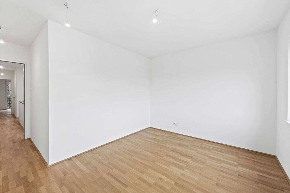 Helles Zimmer mit Holzparkettboden und weiß gestrichenen Wänden.