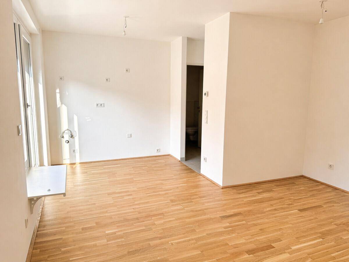 Leerer Raum mit Parkettboden und Anschlüssen an der Wand, bereit für individuelle Gestaltung.