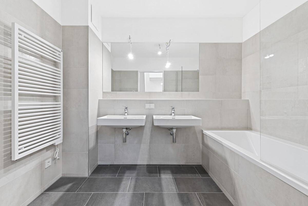 Modernes Badezimmer mit Doppelwaschbecken, Badewanne und beheiztem Handtuchhalter.