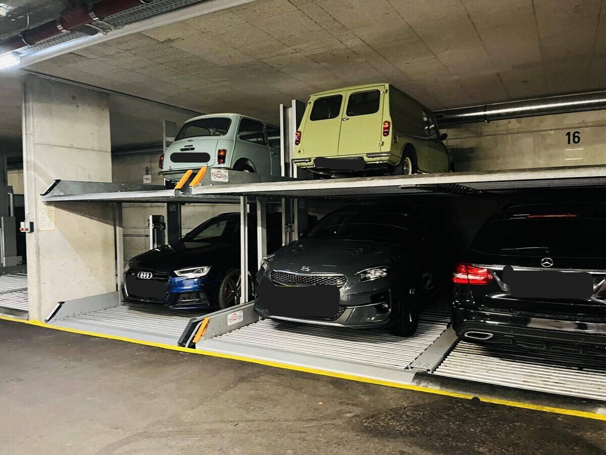 Tiefgarage mit modernen Doppelparkern für mehrere Fahrzeuge, inklusive Oldtimern.