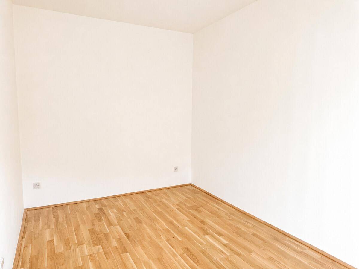 Heller, leerer Raum mit Parkettboden und weißen Wänden, bereit zur individuellen Einrichtung.