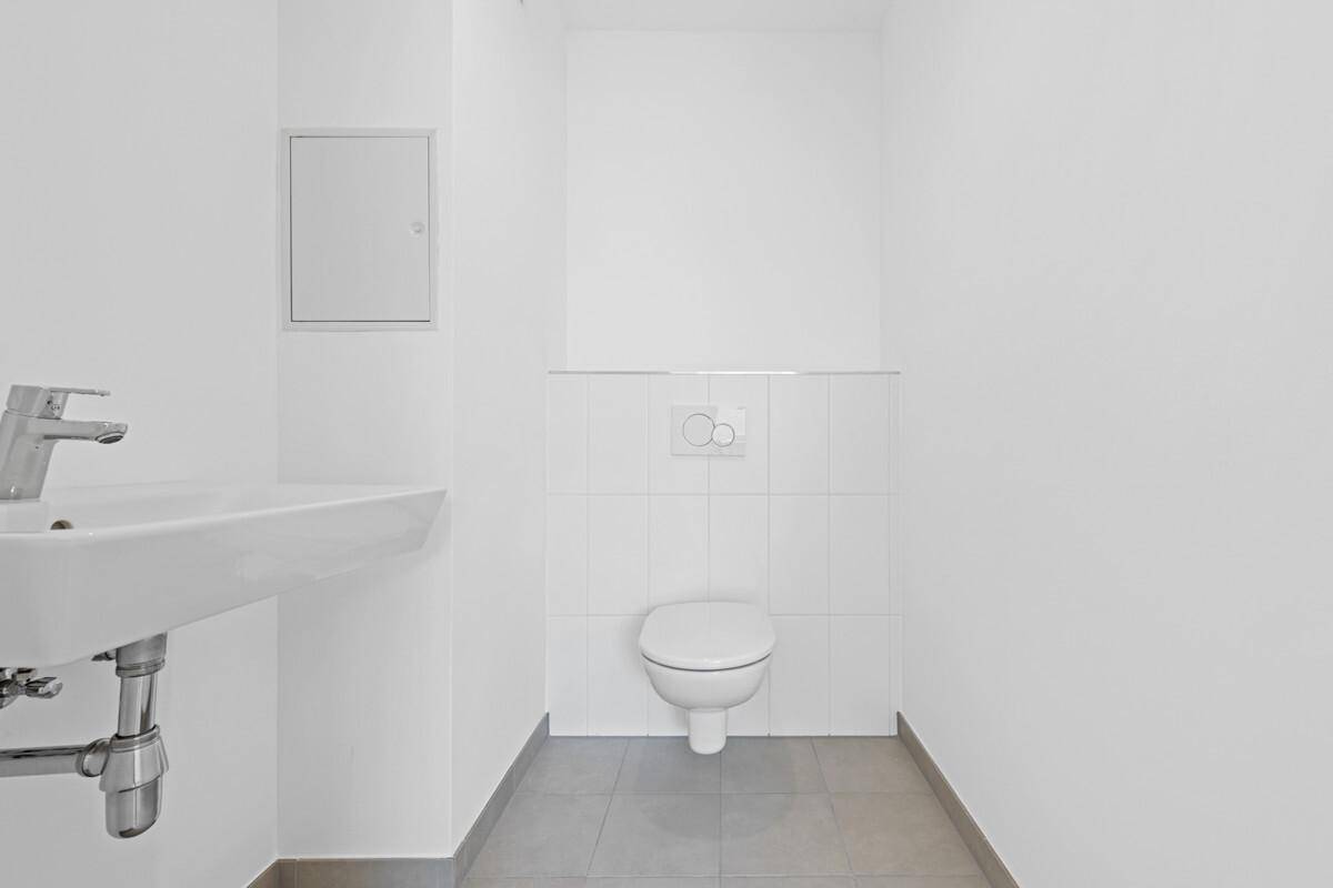 Modernes Gäste-WC mit Wand-WC und Waschbecken, ausgestattet mit hellen Fliesen.