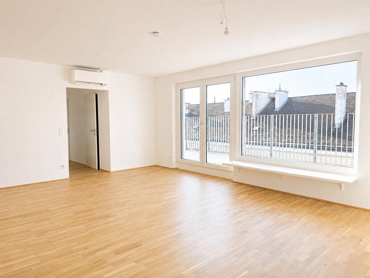 Heller, leerer Wohnraum mit Parkettboden, Klimaanlage und Zugang zur Terrasse.