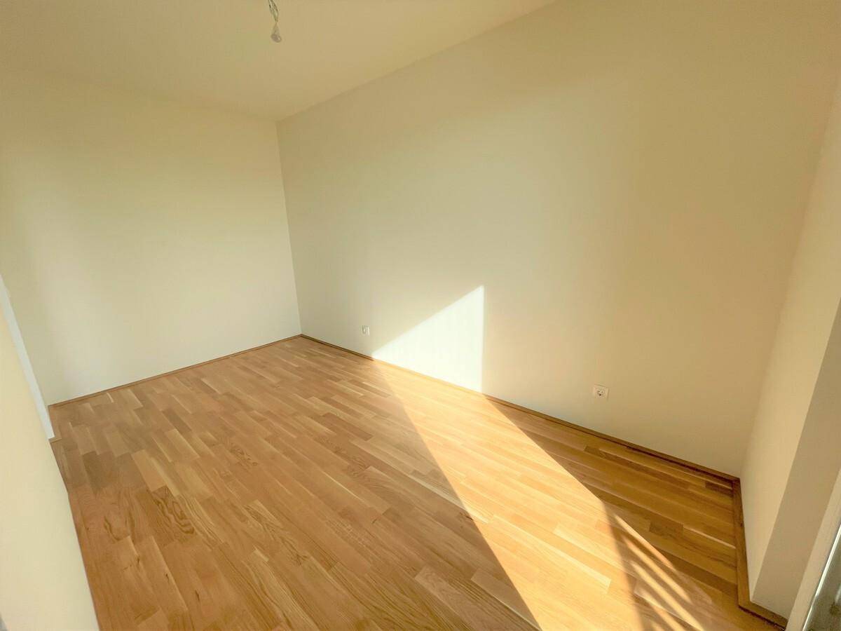 Helles, leeres Zimmer mit Parkettboden und viel natürlichem Licht, ideal als Schlafzimmer.
