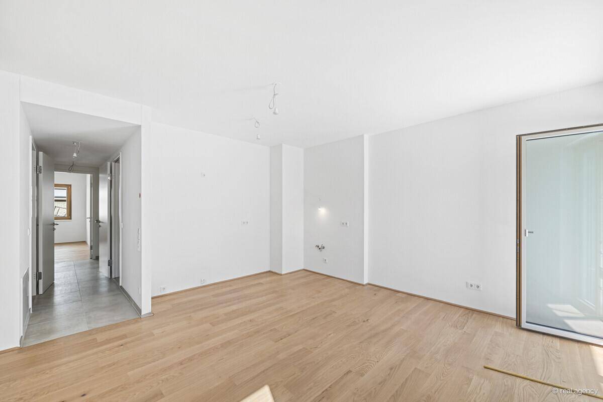 Heller, leerer Raum mit Holzboden und Zugang zu einem Flur, ideal für individuelle Gestaltung.