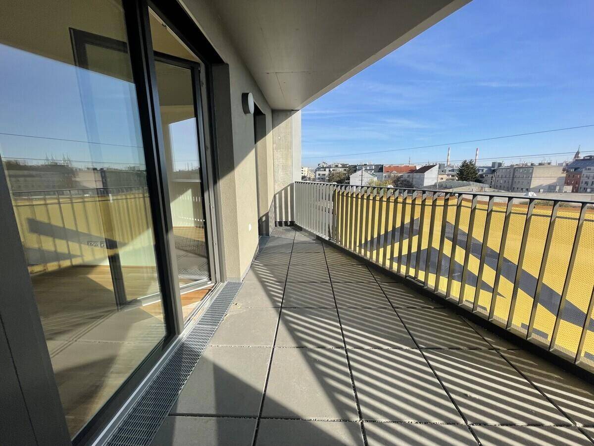 Langer Balkon mit Fliesenboden und Metallgeländer, bietet einen weiten Blick über die Stadt.