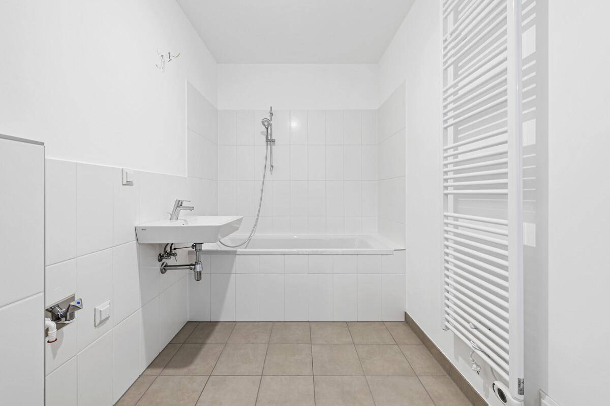 Modernes Badezimmer mit Badewanne, Waschbecken und beheiztem Handtuchhalter.