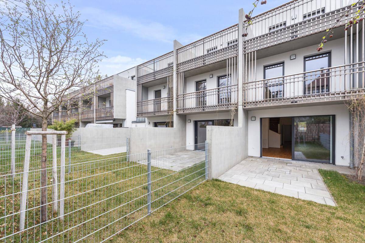 Reihe moderner Reihenhäuser mit privaten Gärten und Balkonen, umgeben von Grünflächen.