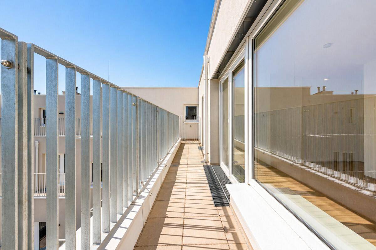 Langer, schmaler Balkon mit Metallgeländer und Blick auf die umliegenden Gebäude.