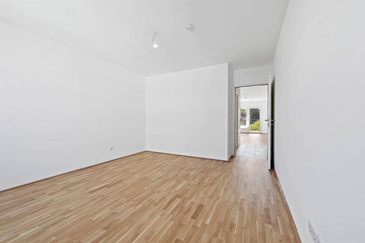 Heller Flur mit Parkettboden und Zugang zu weiteren Räumen, bietet eine offene Atmosphäre.
