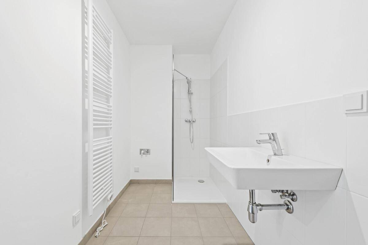Modernes Badezimmer mit Duschkabine, Waschbecken und beheiztem Handtuchhalter.