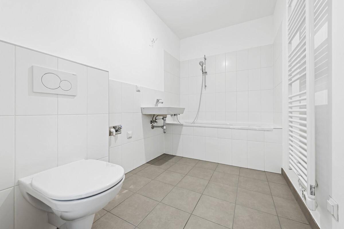 Modernes Badezimmer mit Badewanne, Dusche, WC, Waschbecken und beheiztem Handtuchhalter.
